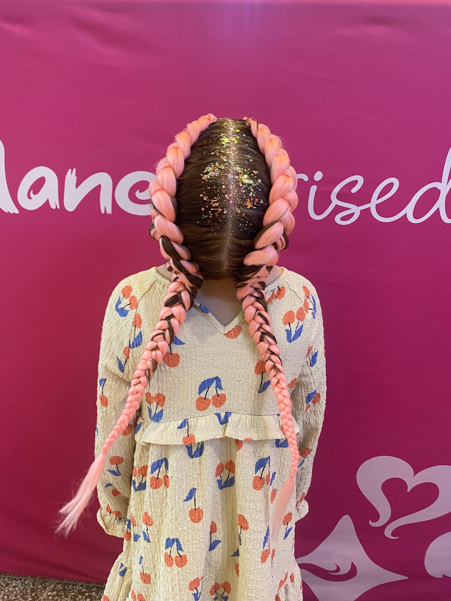 Top view of two coral-pink braids showing the braid pattern and length.